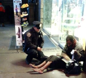 NYPD Office Larry DiPrimo helps a homeless man